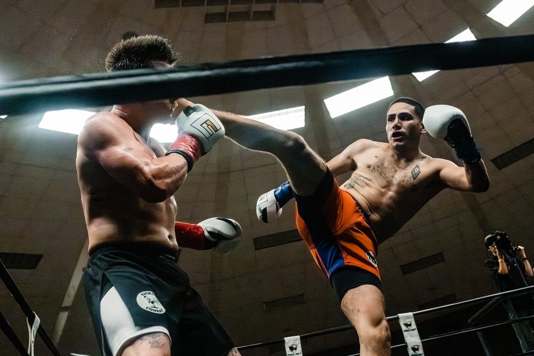 Fighter in orange shorts throwing a high kick