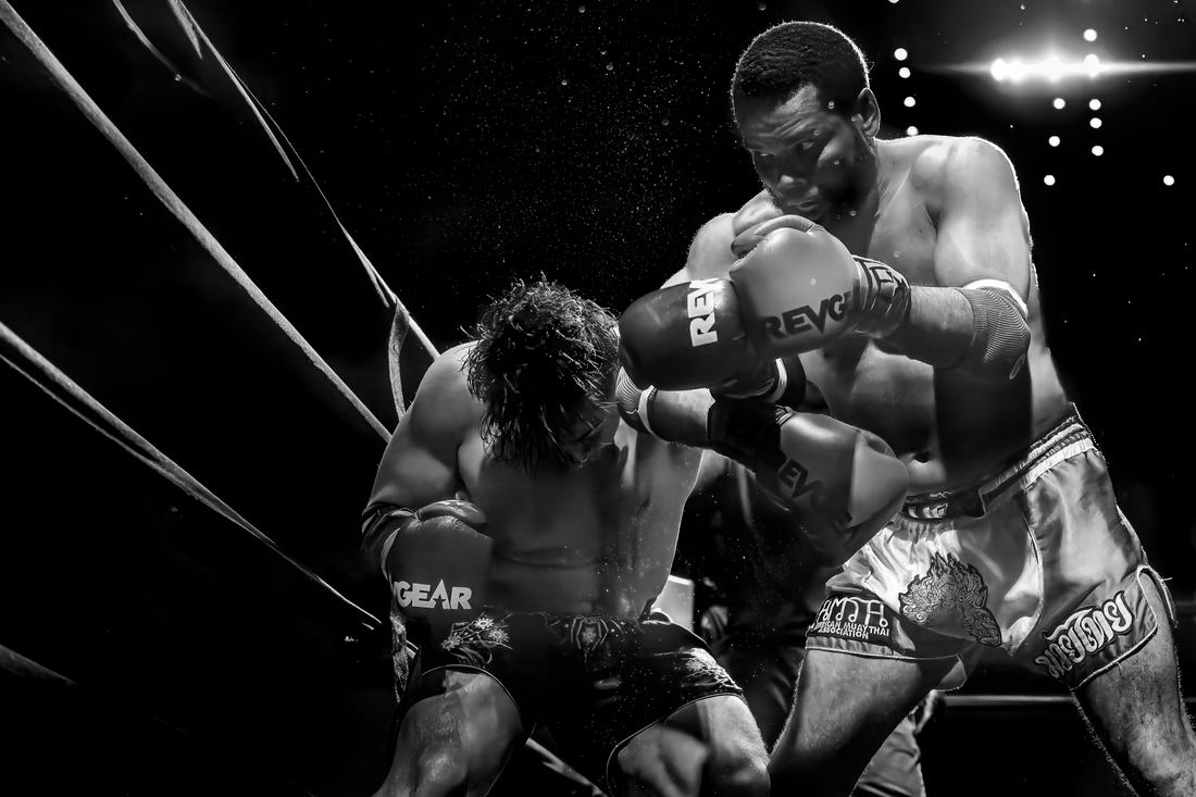 Black and white photo of two fighters clinching against the ropes