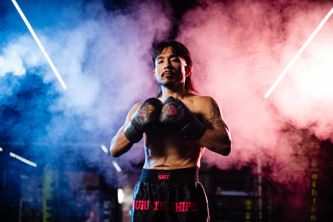 Fighter with wrapped hands standing in blue and red smoke